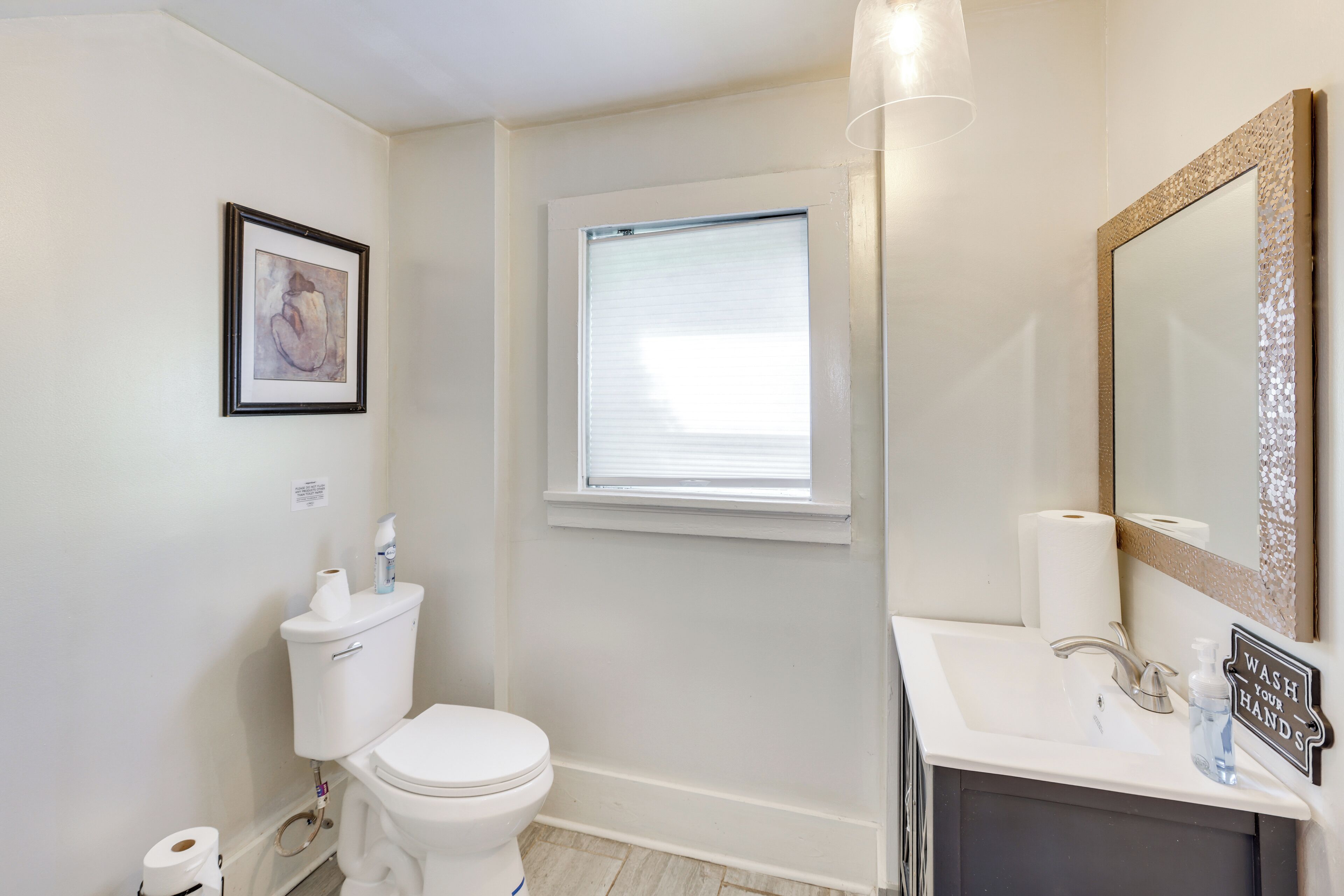 A bathroom with a toilet, sink, and window.