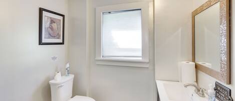 A bathroom with a toilet, sink, and window.