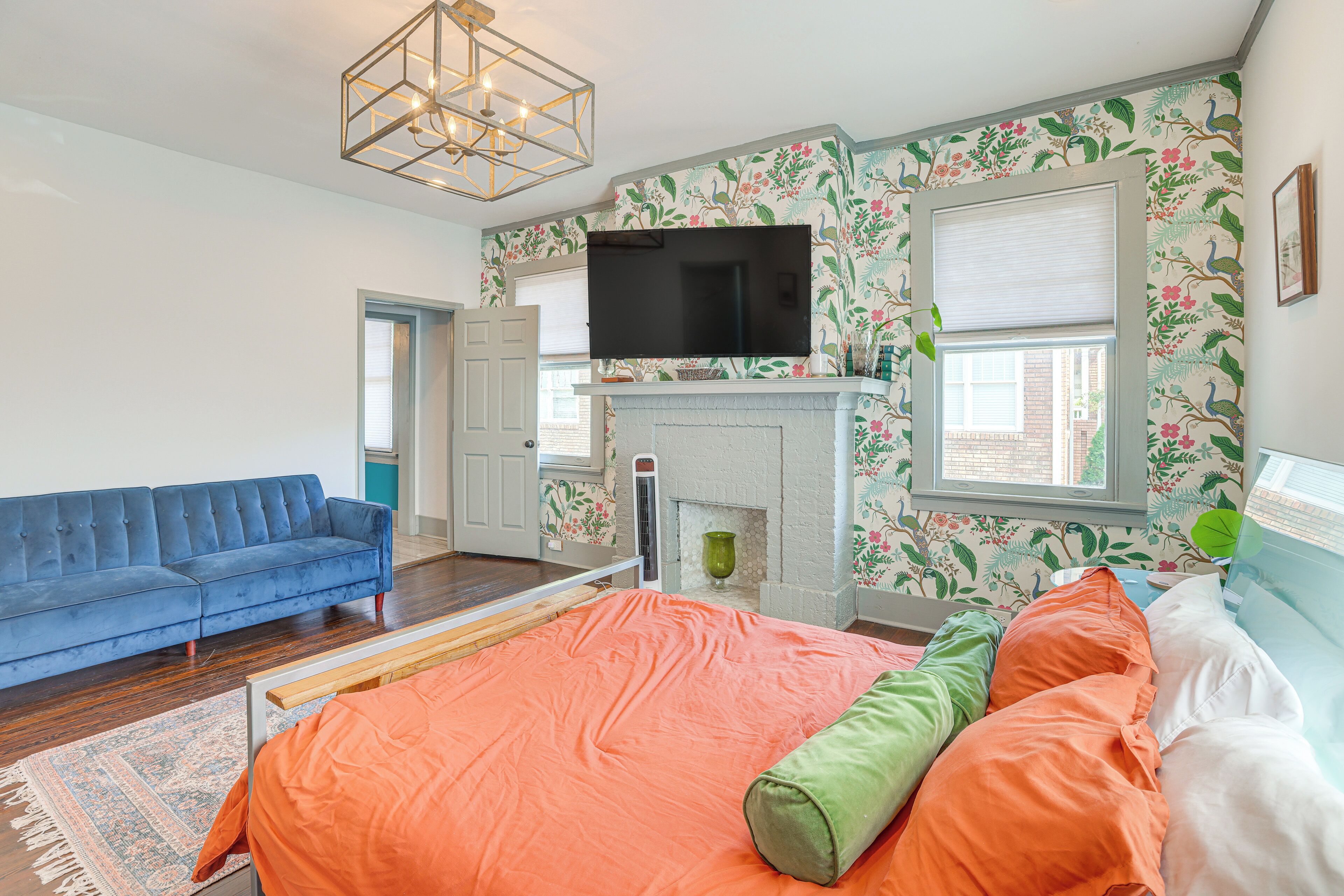 A bedroom with a large bed, a blue sofa, a fireplace, and a TV.