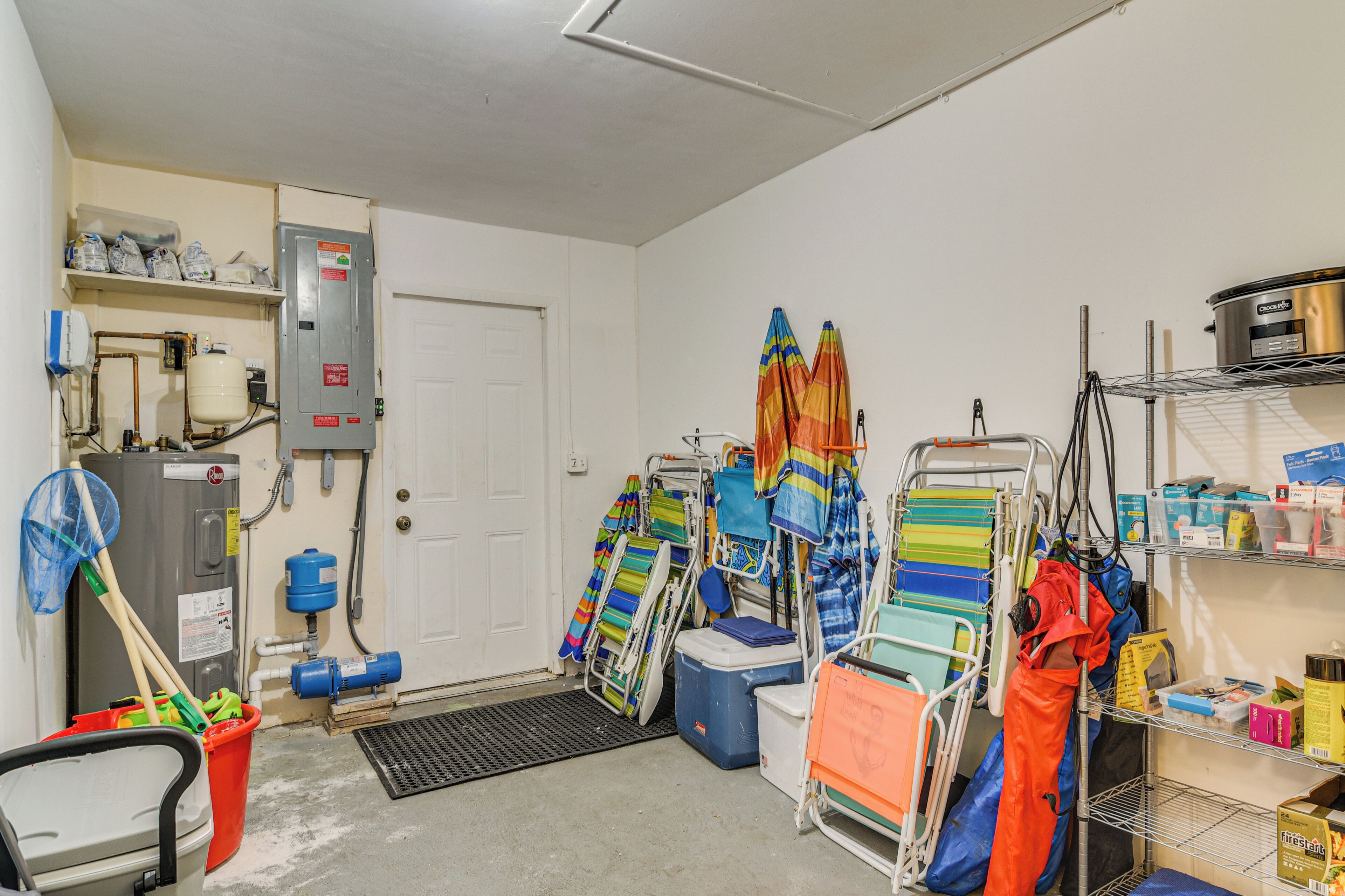 A utility room with a water heater, electrical panel, and storage shelves.