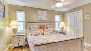 Une chambre à coucher avec un lit en bois, deux tables de chevet avec des lampes, un ventilateur de plafond et une porte décorée d’une étoile.