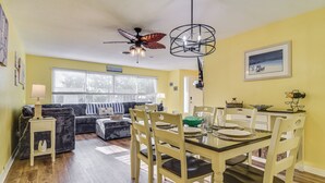 Un coin repas avec une table en verre, des chaises en bois et un ventilateur de plafond.