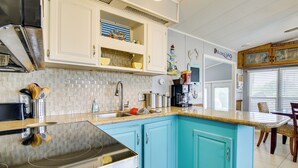 A kitchen with a turquoise island, white cabinets, and a stainless steel stove.