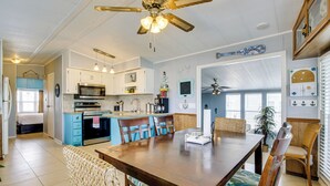 A spacious kitchen with white cabinets, a microwave, and a dining area with a wooden table and wicker chairs.