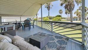 A covered outdoor deck with a seating area, a table, and chairs.