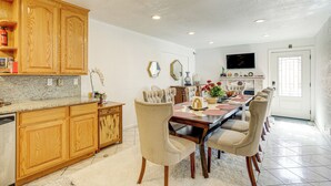 A spacious kitchen with wooden cabinets, a granite countertop, and a dining area with a large table and multiple chairs. - Bay & Hill Views: Modern Hercules Home (Hercules)