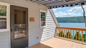 A deck with a sign indicating a deck suite, a door, and a view of a lake and forest.