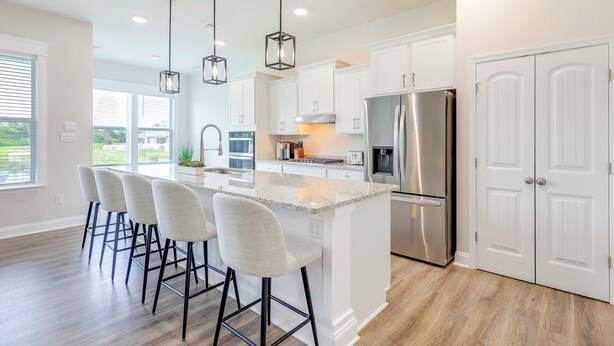 A modern kitchen with white cabinets, a stainless steel refrigerator, and a central island with bar stools. - Recently Built Home w/ View, 3 Mi to Bethany Beach (Ocean View)