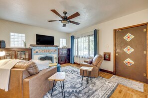 Un salon avec une cheminée, un téléviseur, un ventilateur de plafond et une porte ornée de vitraux.