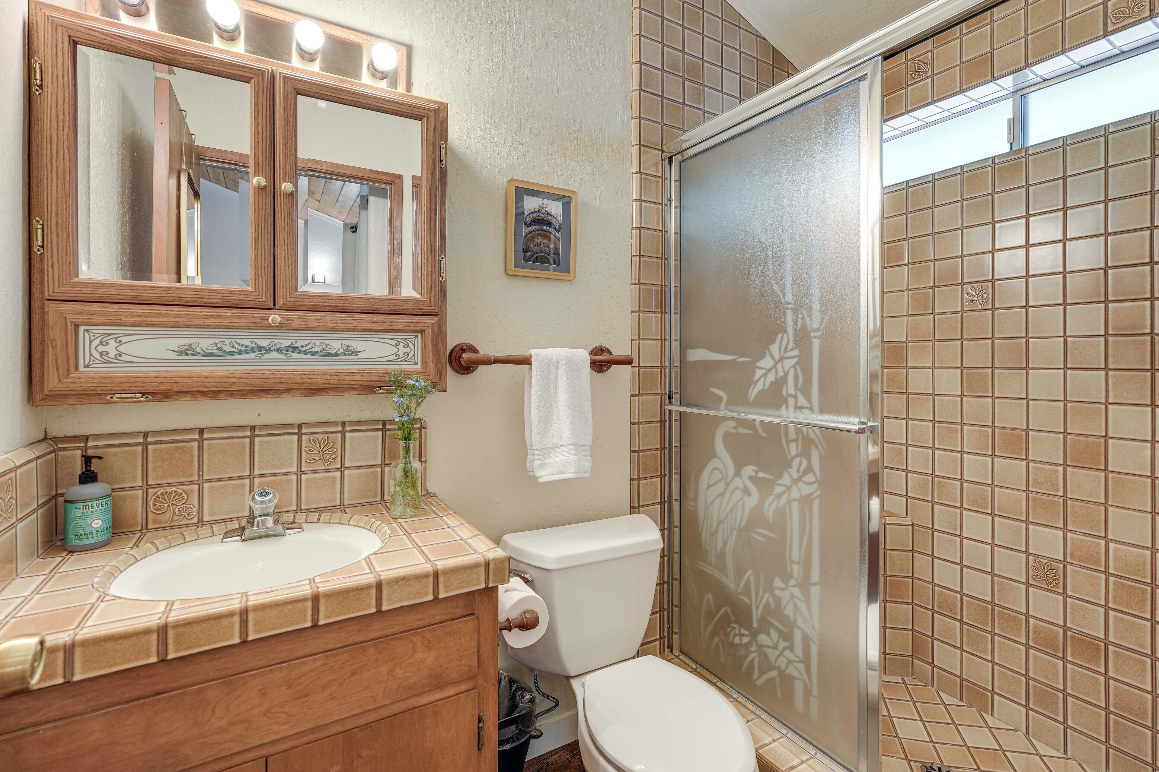 A bathroom with a wooden vanity, a large mirror, a toilet, and a shower enclosure.