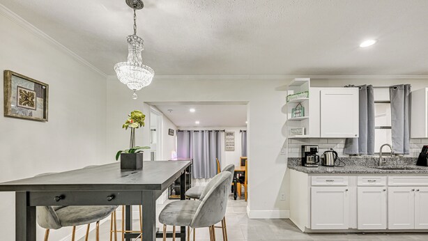 A modern kitchen with white cabinets, a granite countertop, and a chandelier. - Pet-friendly Home w/ Lanais, Near Dtwn Tampa! (Seffner)