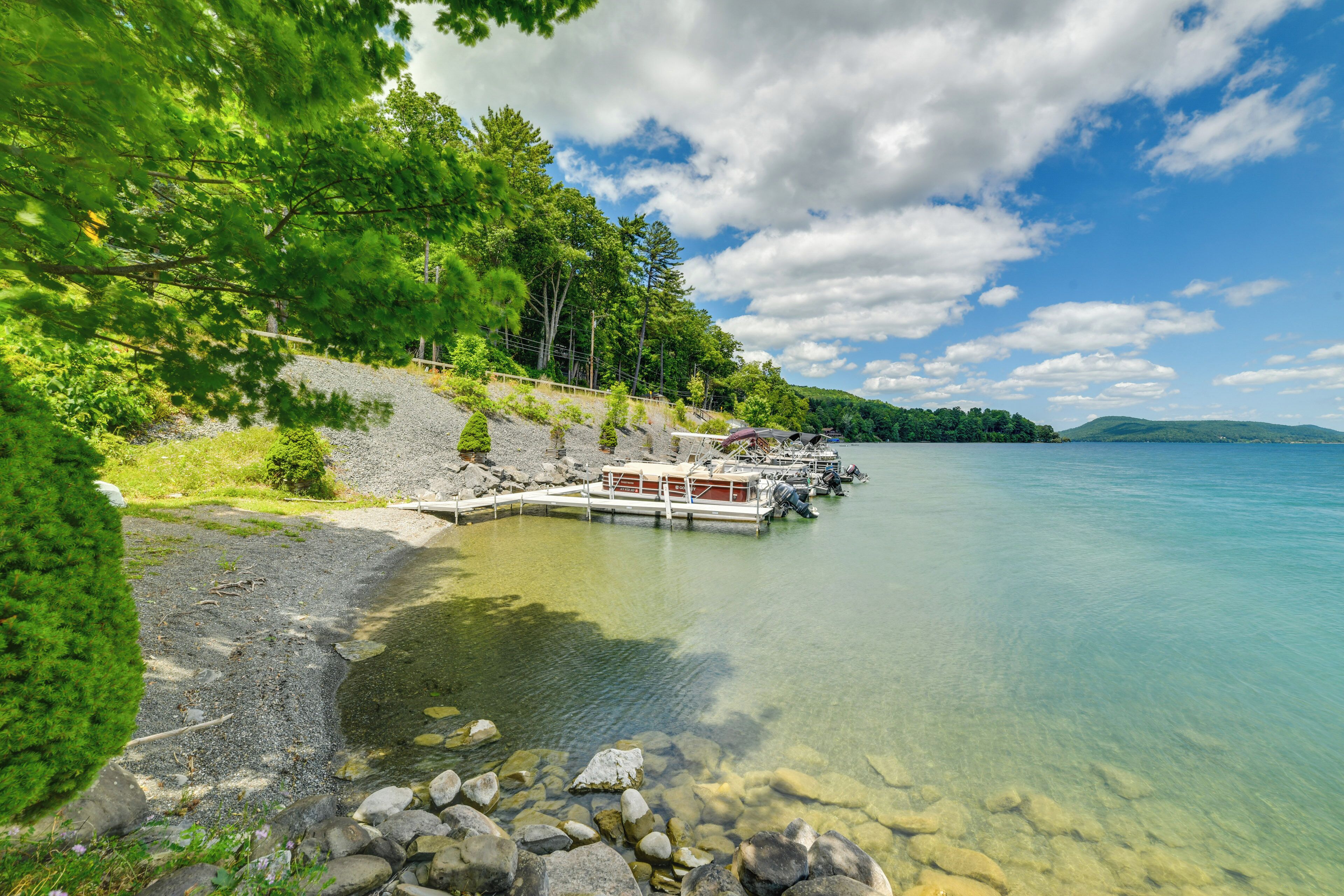 A lakeside dock with boats, clear water, and surrounding greenery.