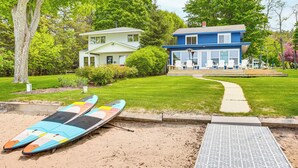 Een strandhuis met twee woningen, een zandgebied met twee surfboards, en een duidelijke pad naar het strand.