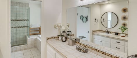 A bathroom with a shower, a sink with a mirror, and a vanity with drawers.