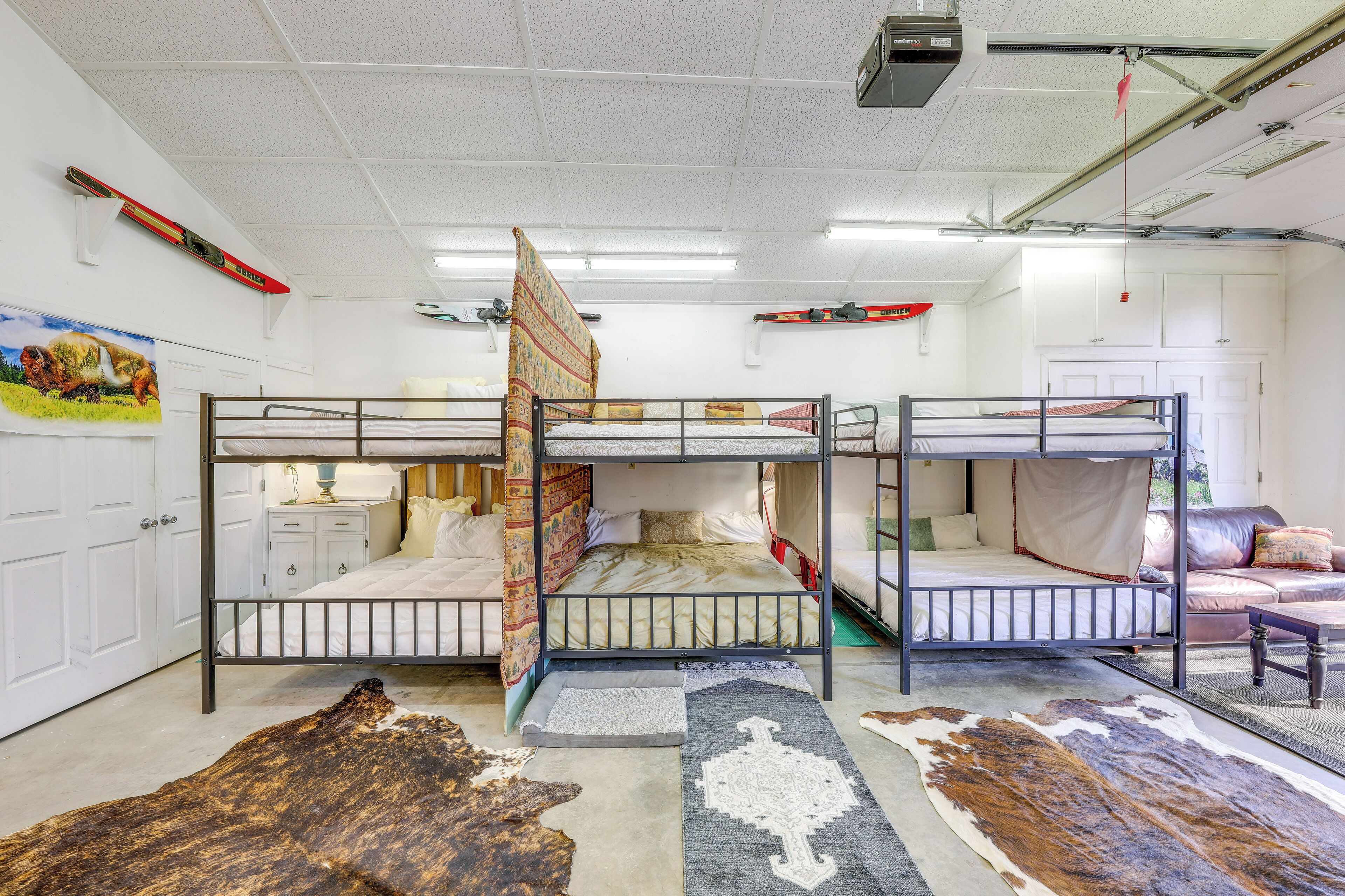 Een kamer met stapelbedden, een witte deur, een ski-rek aan de muur en een groot vloerkleed met dierenprint.