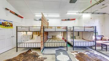 Een kamer met stapelbedden, een witte deur, een ski-rek aan de muur en een groot vloerkleed met dierenprint.