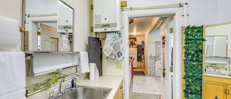 Una cocina moderna con un lavamanos de acero inoxidable, una encimera blanca y un calentador de agua a la vista.