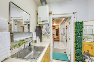 A modern kitchen with a stainless steel sink, a white countertop, and a visible water heater.