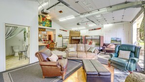 Een ruime woonkamer met leren banken, een blauwgroene fauteuil en een groot vloerkleed.