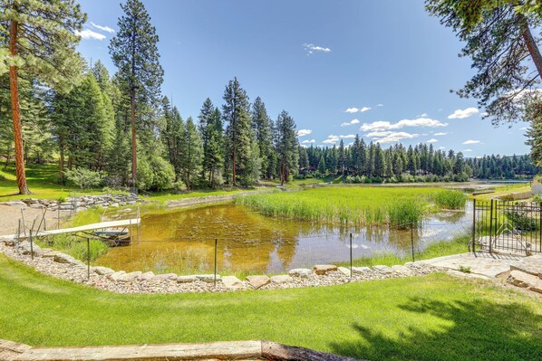 A serene outdoor setting with a pond, surrounded by lush greenery and tall trees.