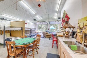 A room with bunk beds, a green felt poker table, a kitchen area with a sink, and a painting of a dog.
