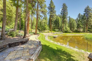 A stone pathway leading to a pond surrounded by tall trees.
