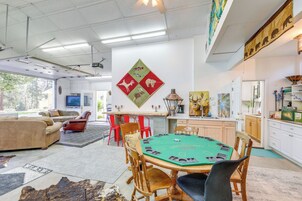 A spacious living area with a pool table, comfortable seating, and a large window offering a view of the outdoors.