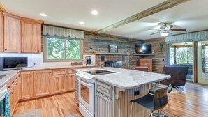 A spacious kitchen with wooden cabinets, a large island, and a built-in oven. - On Lake Tillery: Spacious Home w/ Screened Porch! (Albemarle)