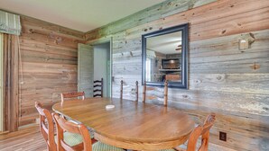 A wooden dining table with chairs, a mirror, and a view into the kitchen. - On Lake Tillery: Spacious Home w/ Screened Porch! (Albemarle)