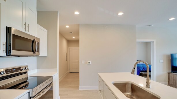A modern kitchen with white cabinetry, stainless steel appliances, and a large sink. - Gateway to Fort Worth & Burleson! Couples Apt (Crowley)