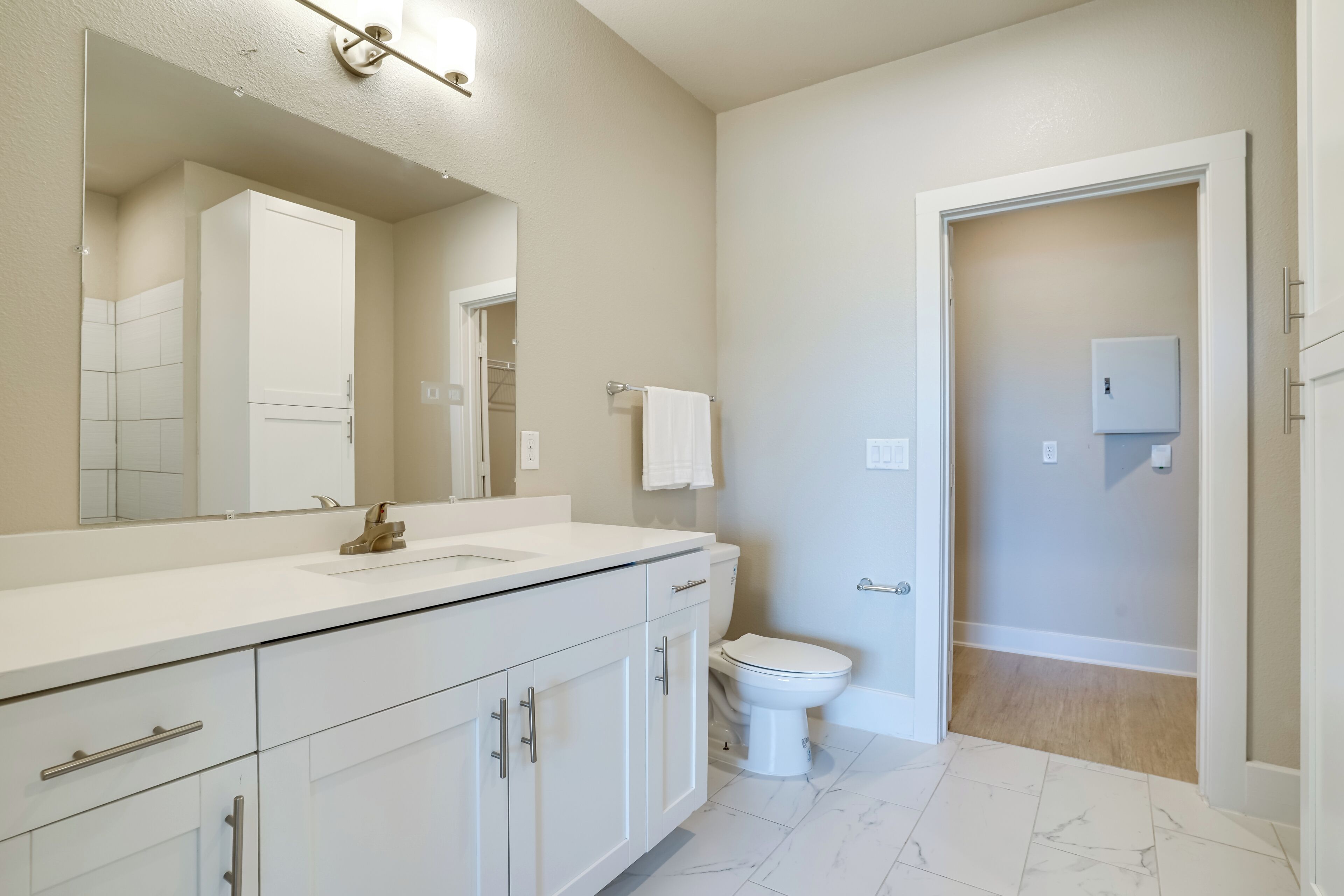 Une salle de bain moderne avec un meuble-lavabo blanc, un grand miroir et des toilettes.