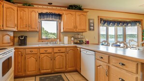A kitchen with wooden cabinets, a dishwasher, and a window with a view of the outdoors. - Lake Memphremagog Access: Newport Condo w/ Balcony (Newport Center)