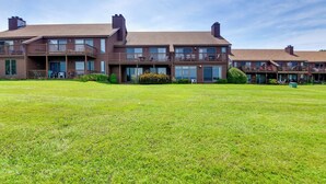 A multi-story residential building with balconies, large windows, and a well-maintained lawn. - Lake Memphremagog Access: Newport Condo w/ Balcony (Newport Center)