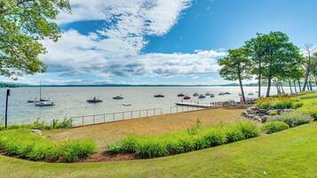 A lakeside view with boats, a grassy area, and trees.