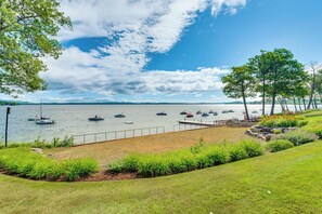 A lakeside view with boats, a grassy area, and trees. - Waterfront Community: Lake Winnipesaukee Retreat! (Gilford)