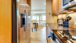 A modern kitchen with wooden cabinets, stainless steel appliances, and a glass backsplash. - Waterfront Community: Lake Winnipesaukee Retreat! (Gilford)