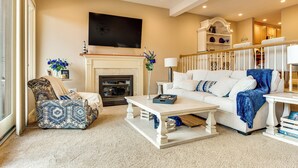 A living room with a fireplace, a sofa, a coffee table, and a patterned armchair. - Waterfront Community: Lake Winnipesaukee Retreat! (Gilford)