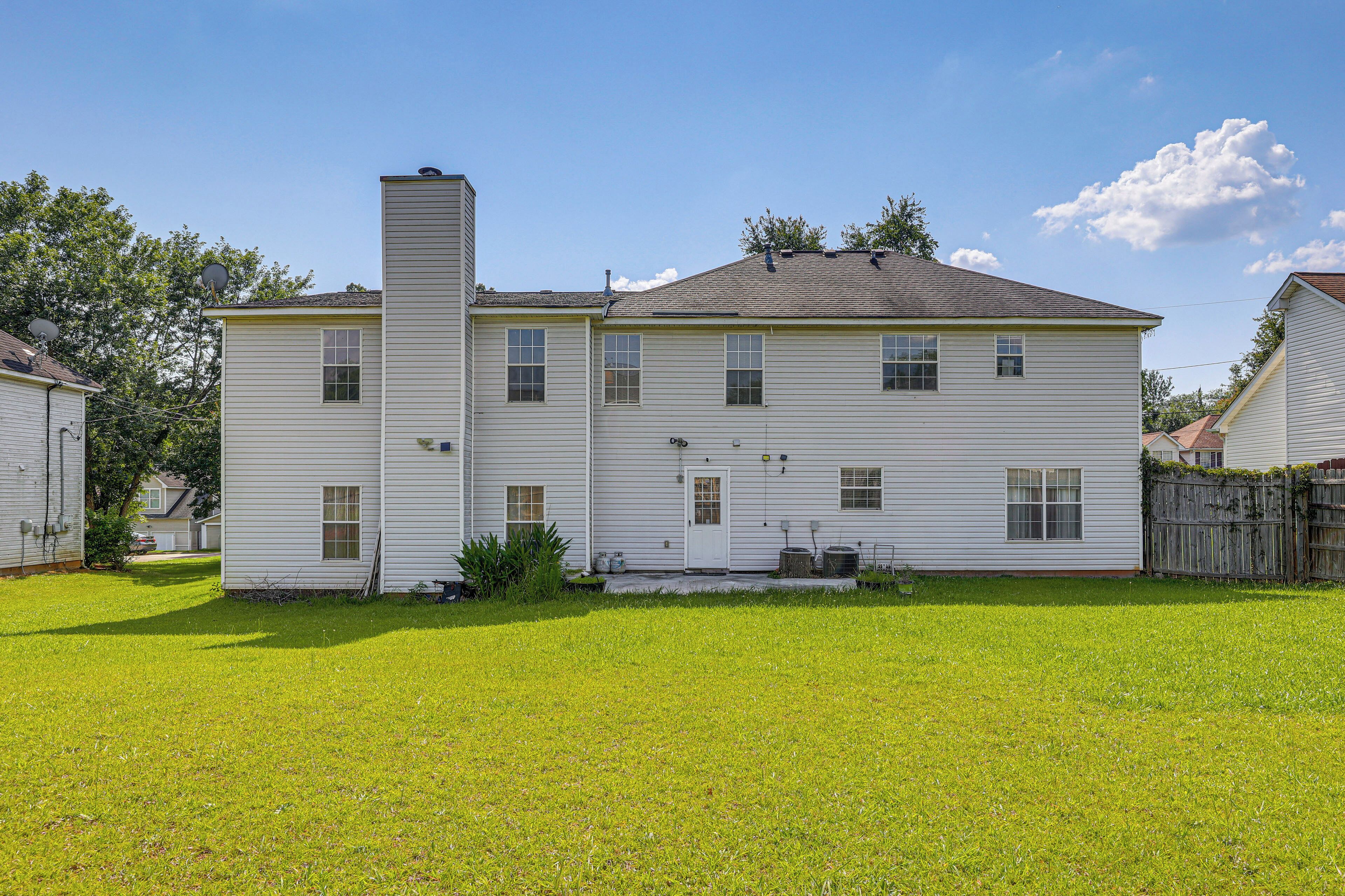 A two-story house with a chimney, a front yard, and a wooden fence.