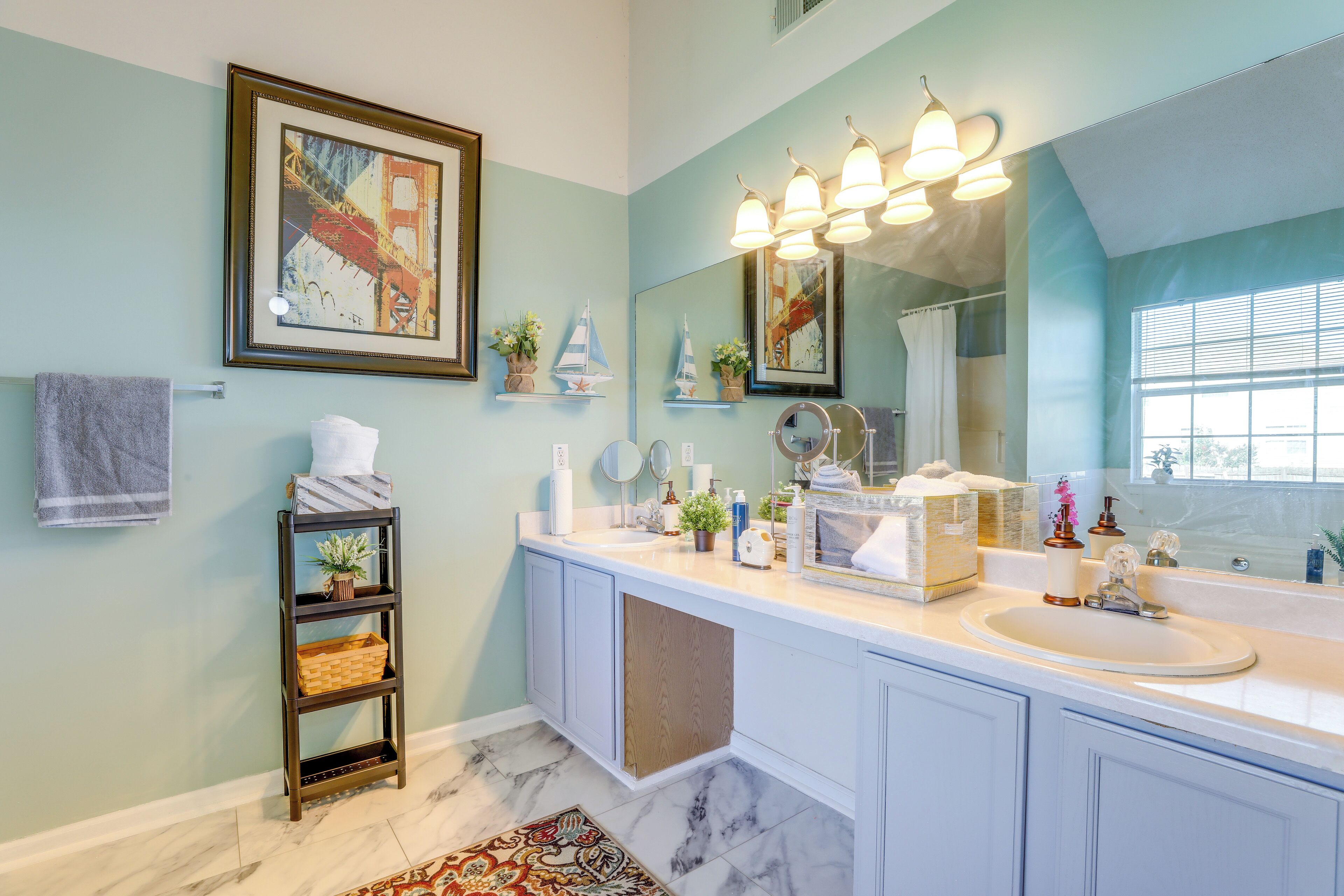 A bathroom with a large mirror, a sink, a towel rack, and a shelf with decorative items.