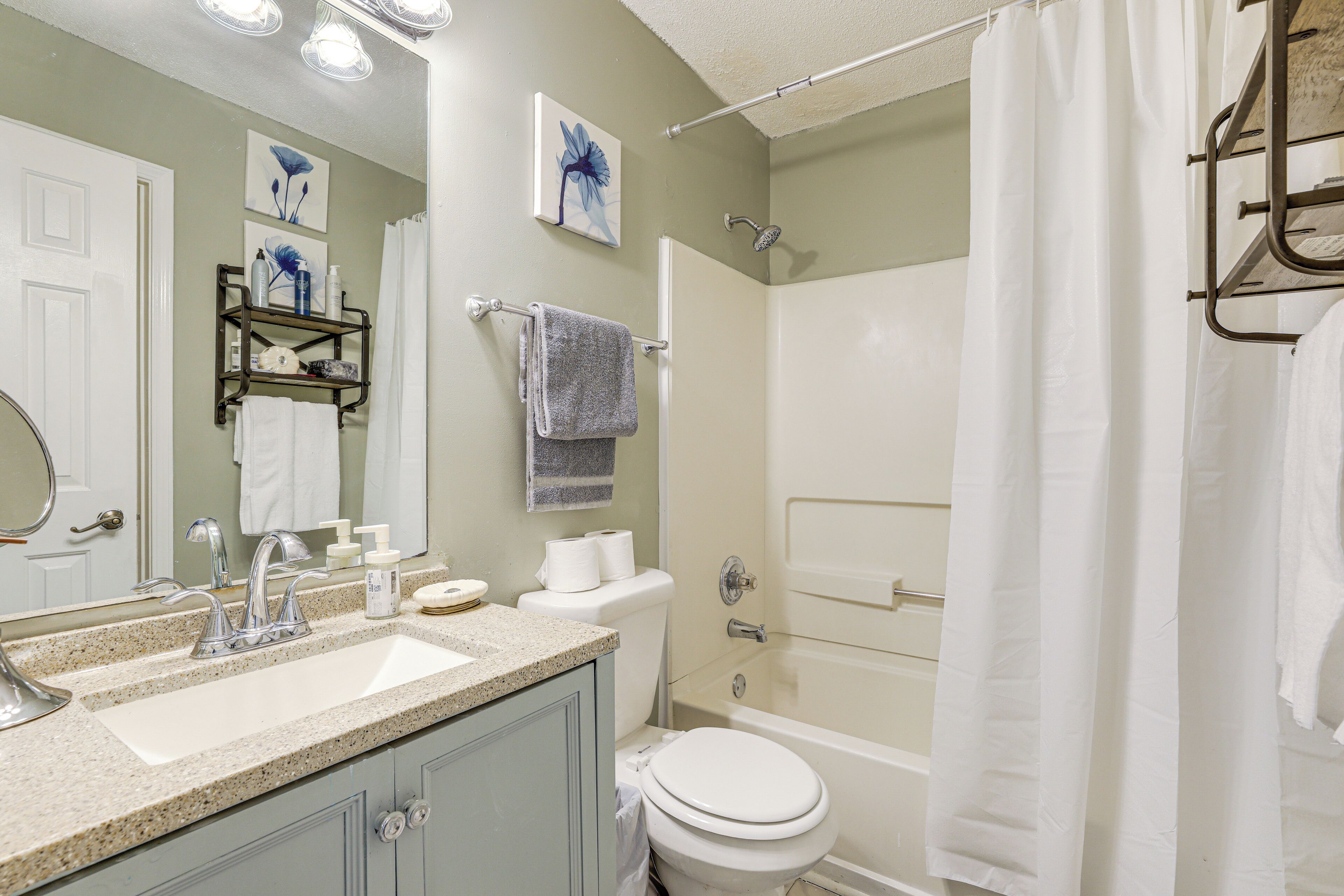 Un bagno con lavandino, WC e vasca. Asciugamani e articoli da toilette sono presenti sul ripiano.