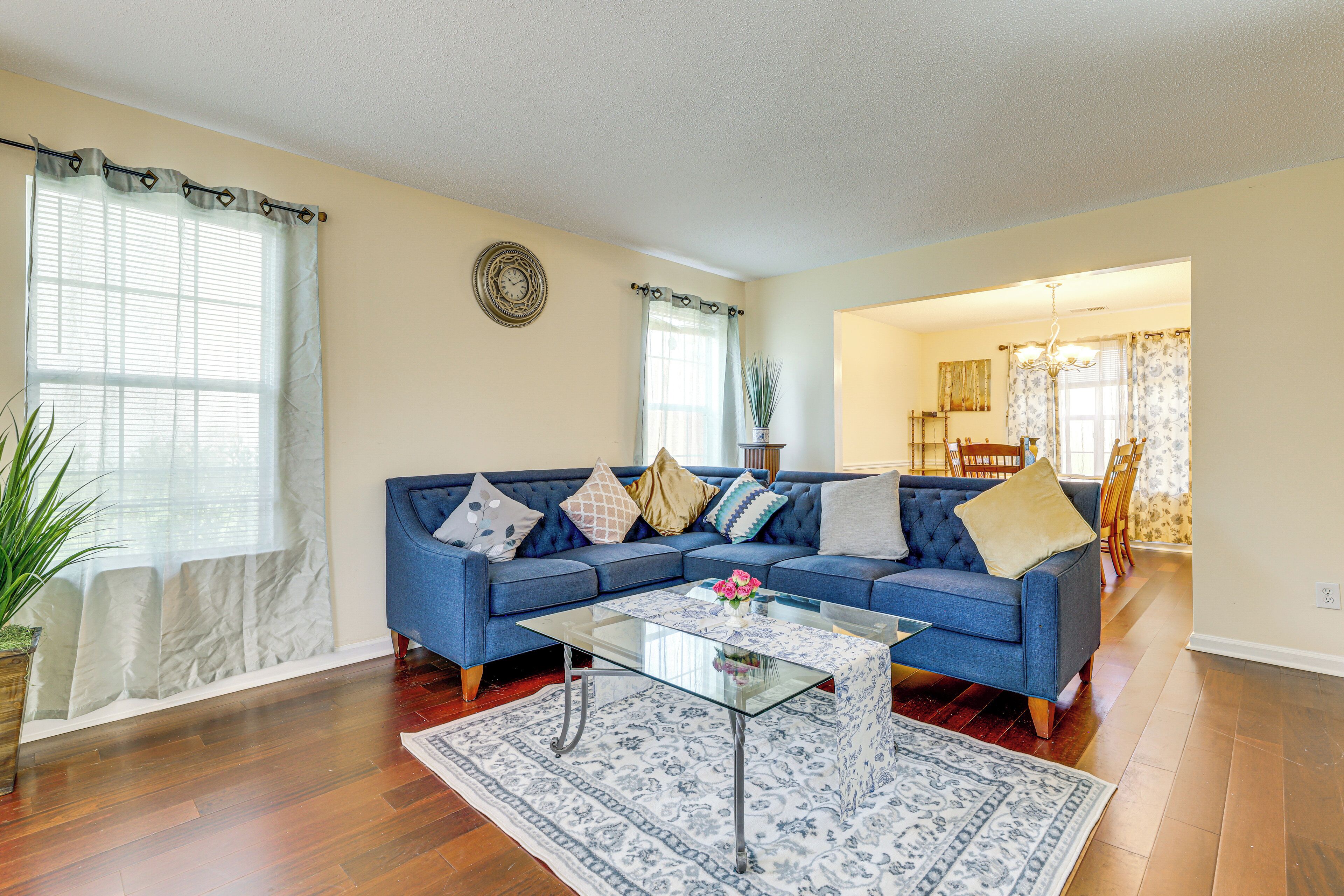 A living room with a blue sofa, a glass coffee table, and a patterned rug.