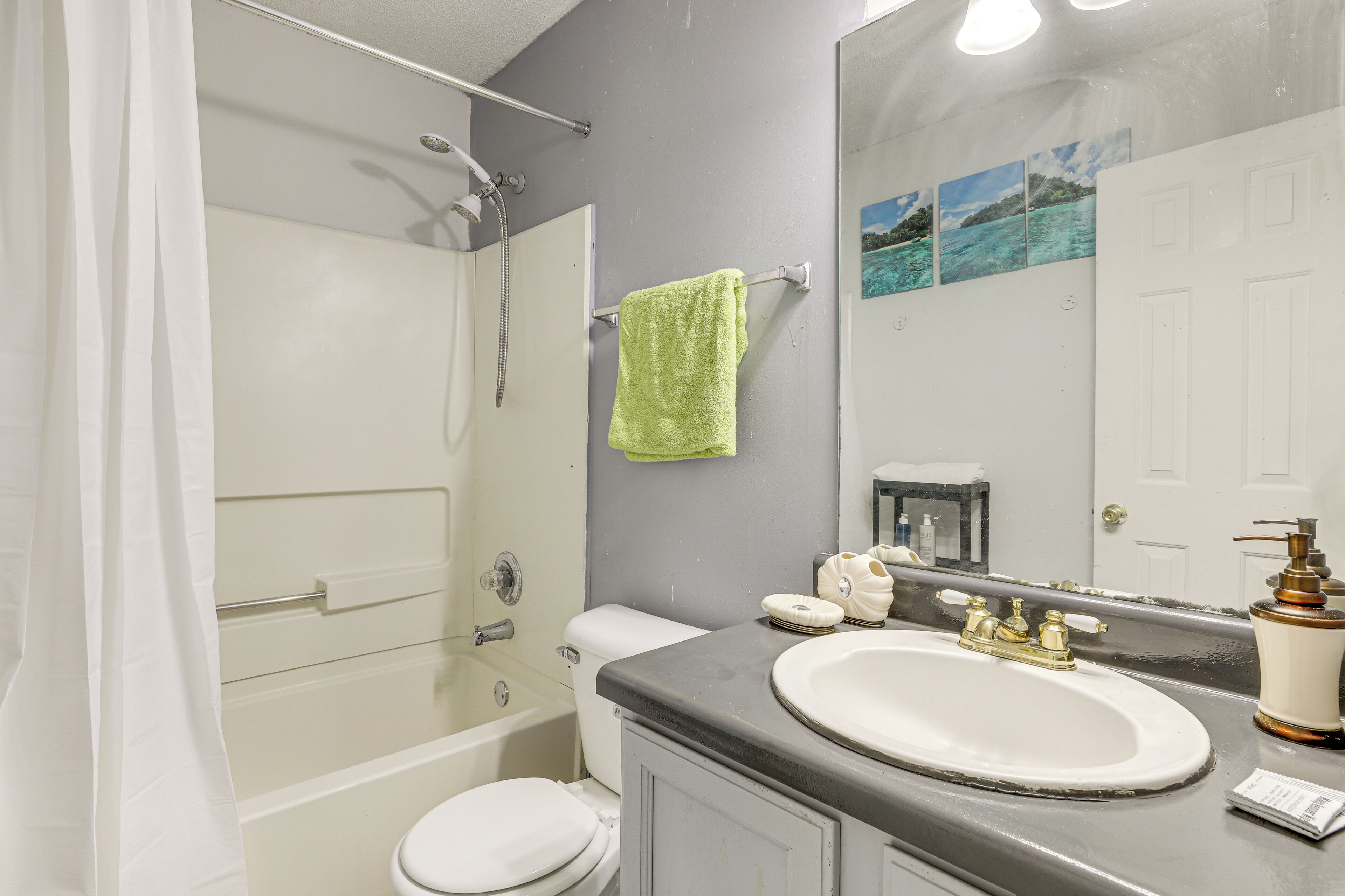 A bathroom with a bathtub, toilet, sink, and a large mirror.