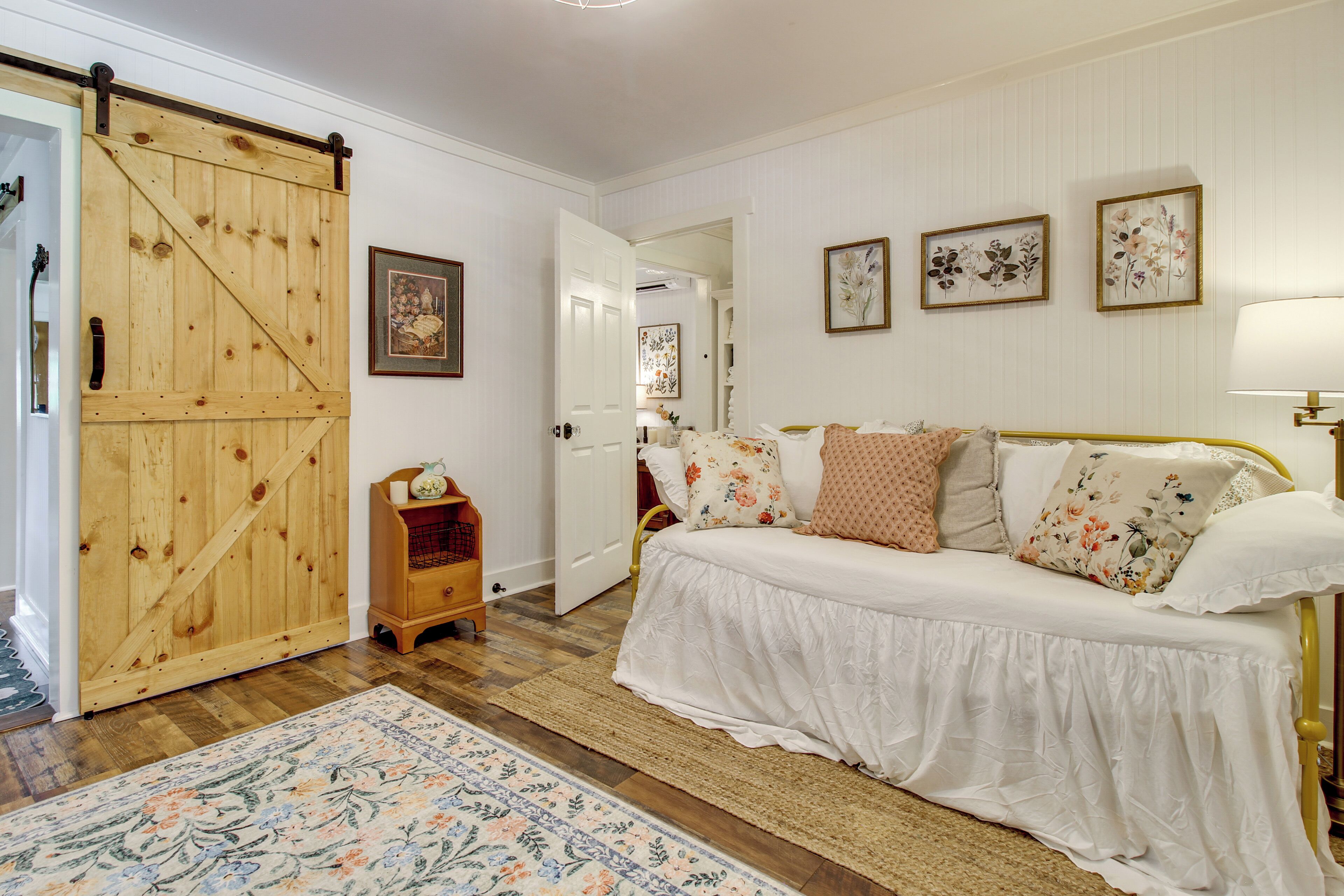 Una camera da letto con un letto, una porta in legno, un piccolo armadietto in legno e un tappeto floreale.