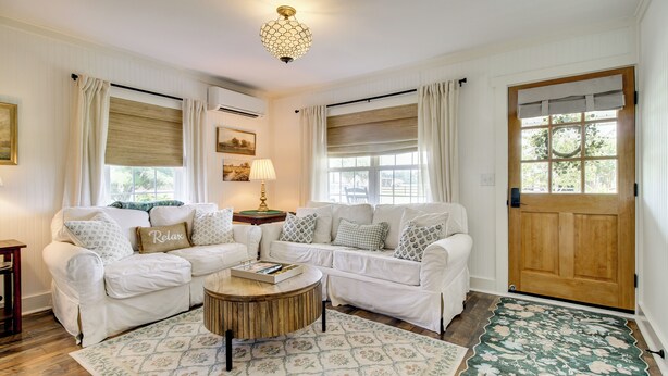 A room with two white sofas, a wooden coffee table, and a patterned rug. - Shepard Cottage Near Wilmington & Wedding Venue (Burgaw)