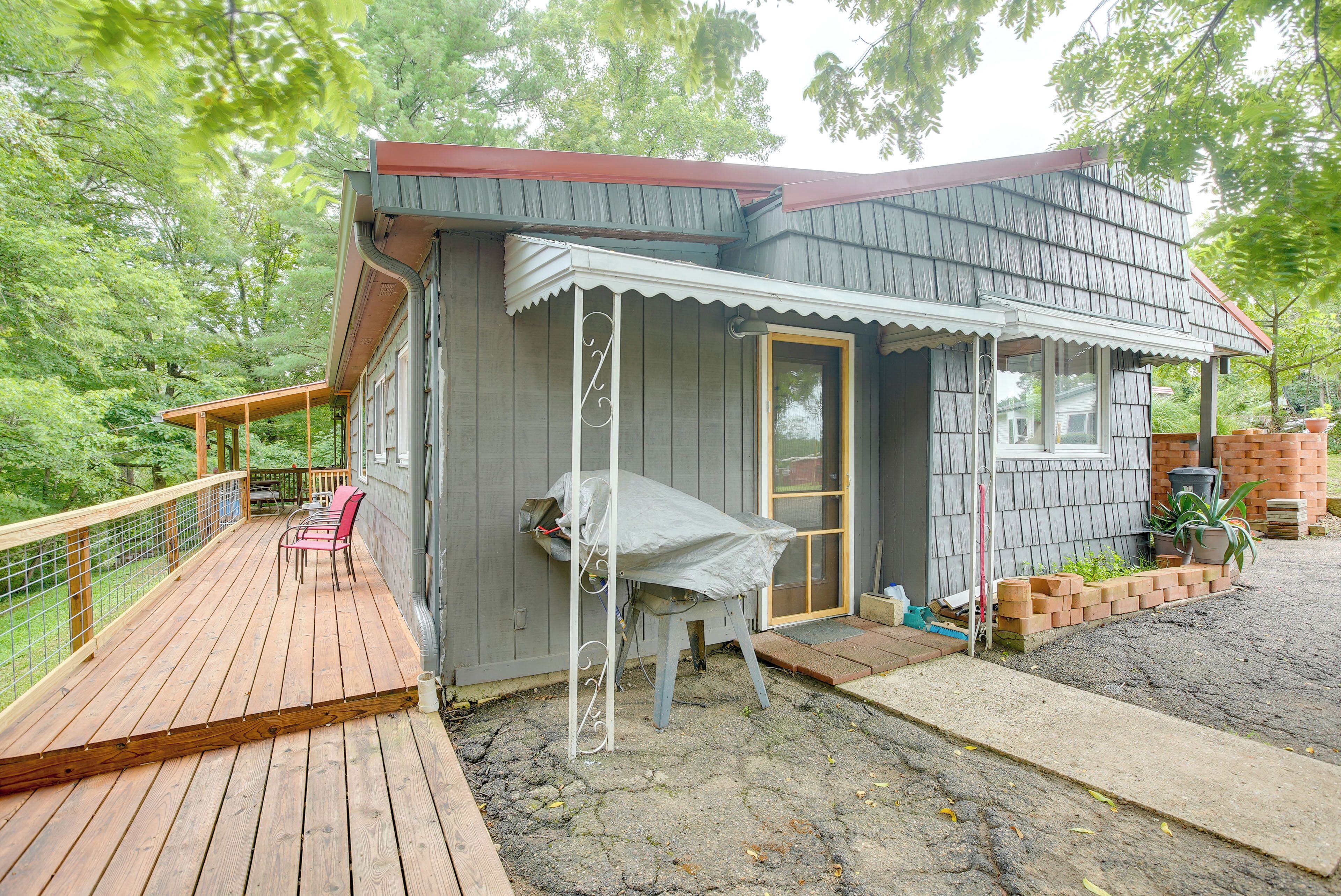 A wooden deck with a covered seating area, a small shed, and a brick planter with plants.