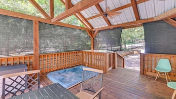 Une terrasse en bois avec un jacuzzi, une table et des chaises.