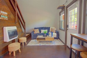 A cozy living room with a wooden staircase, a blue sofa, a coffee table, and a small wooden table.