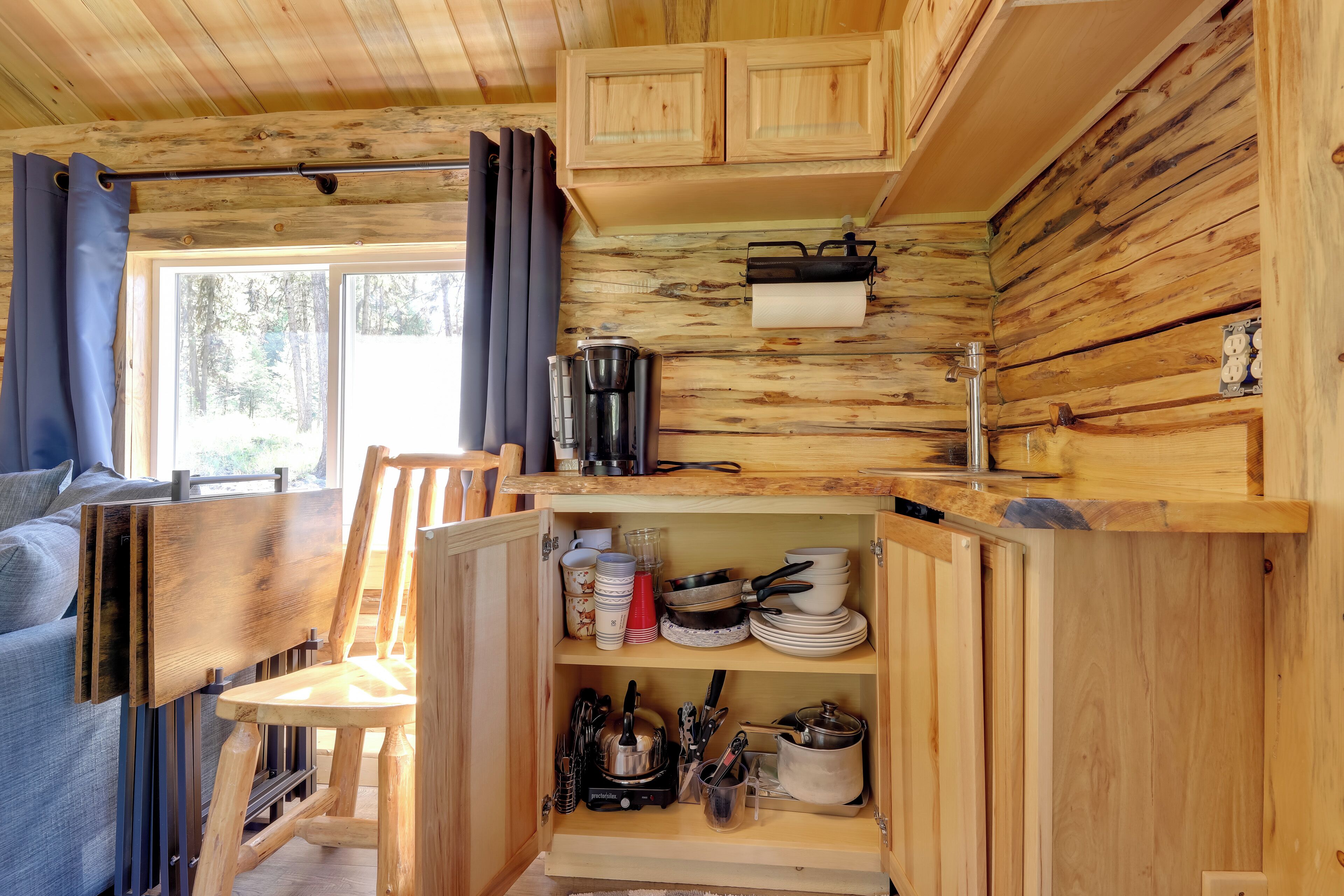 A compact kitchen with wooden cabinetry, a coffee maker, and a stove.