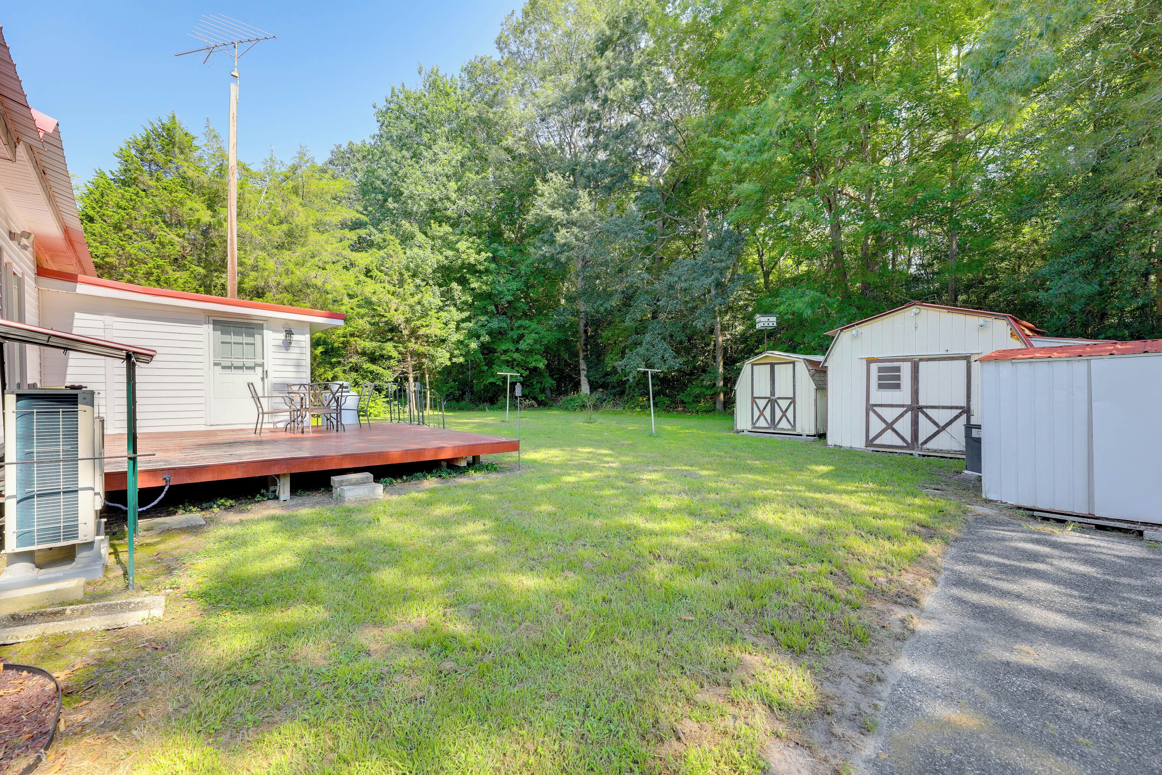 A residential backyard with a covered patio, a shed, and a utility building.