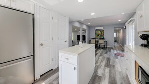A modern kitchen with white cabinetry, a built-in island, and a dining area with a table and chairs. - 12 Mi to Dtwn Lewes & Beach: Delaware Home w/ Deck (Georgetown)